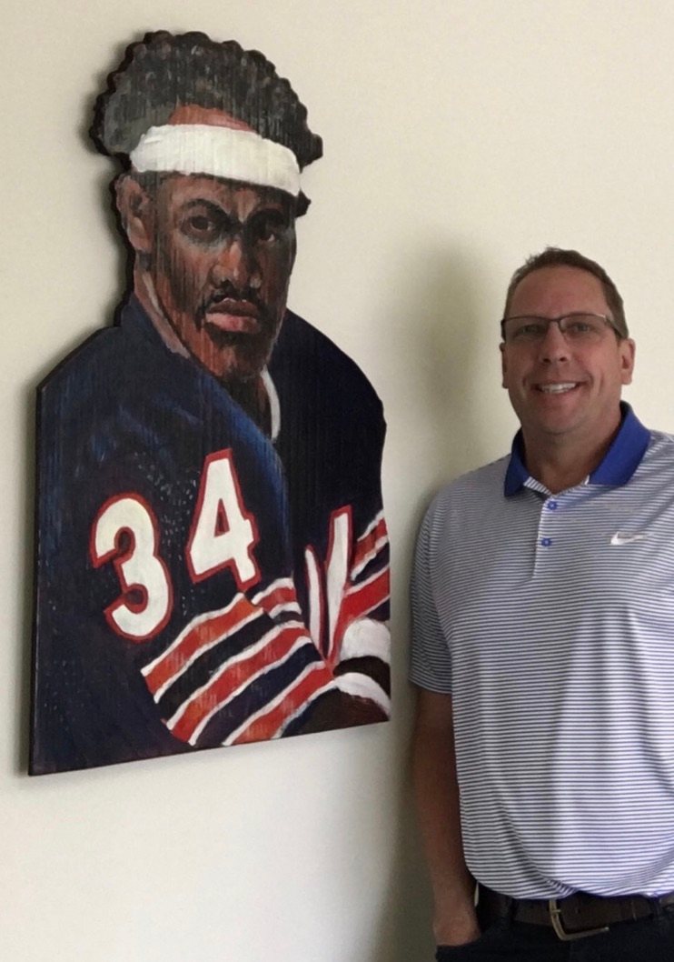 Hand-cut and hand-painted portrait of Walter Payton, number 34, in a navy Chicago Bears jersey with a white headband, shown on a wall beside the customer